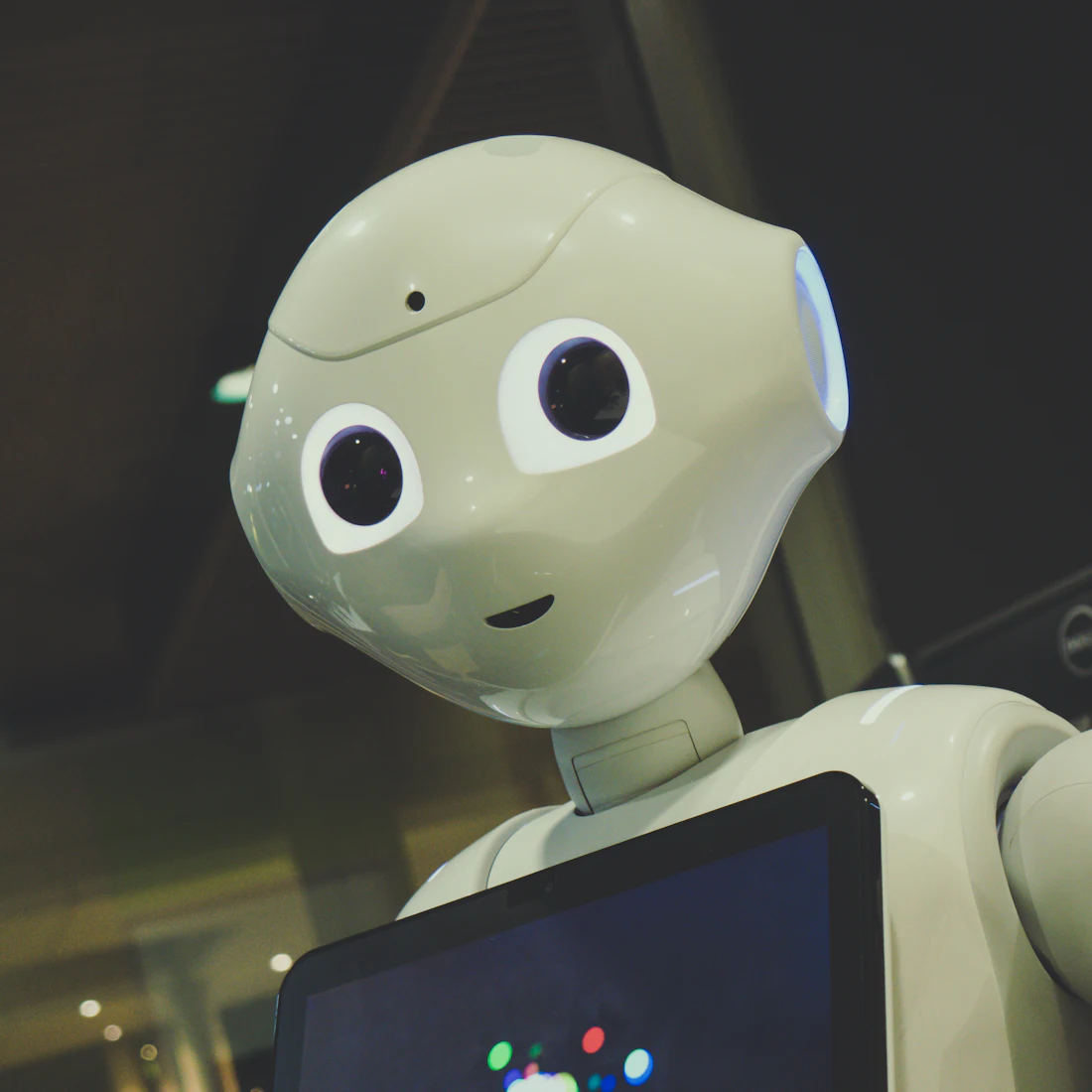 A friendly white humanoid robot looking at the camera